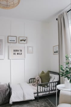 a small bedroom with white walls and pictures on the wall above the bed, along with a teddy bear