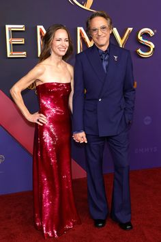 a man and woman in formal wear posing on the red carpet