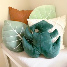 two pillows and a stuffed elephant are on a white bench in front of a wall