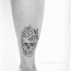 a black and white photo of a person's foot with a flower skull tattoo on it