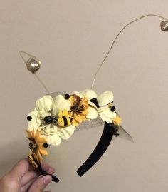 a hand holding a flower headband made out of fake flowers and black hair pins