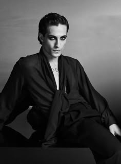 a woman sitting on top of a table wearing a black shirt and tie around her neck