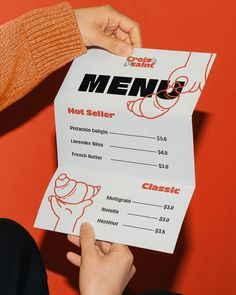 two people holding up a menu for a restaurant with the word menu written on it