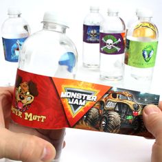 a hand holding up a water bottle with monster jam on it and other bottles behind it