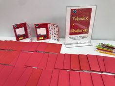 several pieces of red paper sitting on top of a table next to some pens and pencils