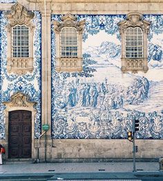 a blue and white building with two people walking past it on the sidewalk in front of it