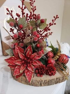 a christmas arrangement with poinsettis, berries and greenery on a tree stump