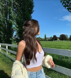 a woman standing next to a wooden fence