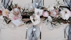 the table is set with silverware, flowers and napkins for an elegant dinner