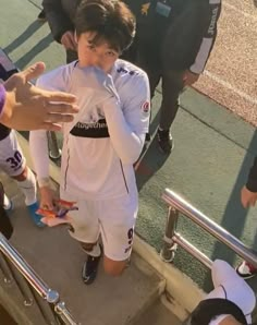 a young boy is walking down the stairs with his hand on his face and other people around him