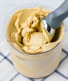 an ice cream in a glass container with a spoon sticking out of it and sitting on a checkered table cloth