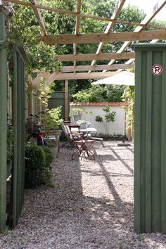 an outdoor patio with tables and chairs under a pergolated roof over graveled area