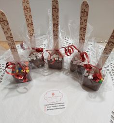 four candy sticks wrapped in cellophane and tied with red ribbon on top of a table