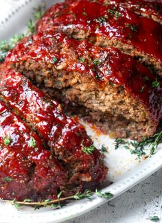 the meatloaf is covered with ketchup and garnished with fresh herbs