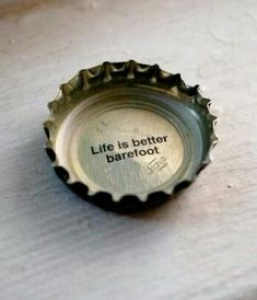 a bottle cap with the words life is better barefoot written in black ink on it