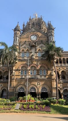 an old building with a clock on the front and palm trees in the foreground