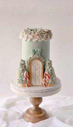 a cake decorated with candy canes and candies is on a pedestal in front of a white backdrop