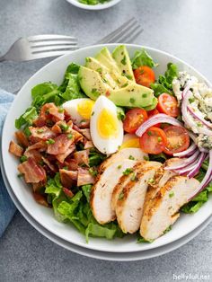 a white plate topped with salad and sliced chicken