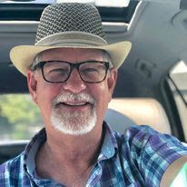 an older man wearing glasses and a hat is sitting in the back seat of a car