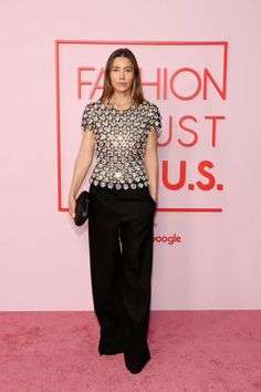 a woman in black pants and a top on a pink carpet with the words fashion just us