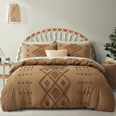 a bed with brown comforter and pillows in a room next to a plant on the floor