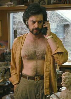 a man with no shirt talking on a cell phone