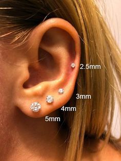 a woman's ear is shown with three small diamond studs on the side