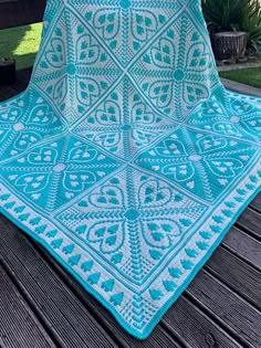 a blue crocheted blanket sitting on top of a wooden bench