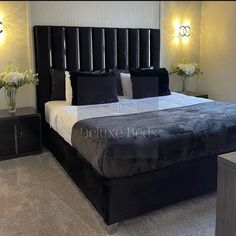 a large bed with black headboard and pillows