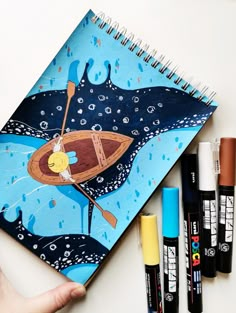 a notebook with an image of a whale on it and marker pens next to it