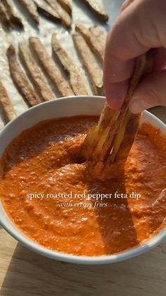 a person dipping some kind of food into a bowl with breadsticks in it