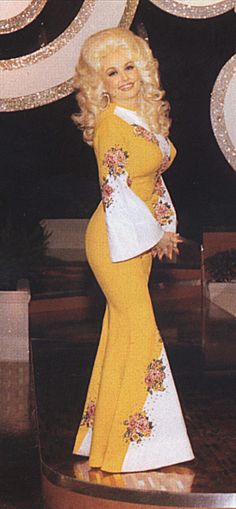 a woman in a yellow and white dress standing on a stage