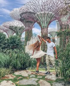 a man and woman are dancing in front of trees with their arms around each other