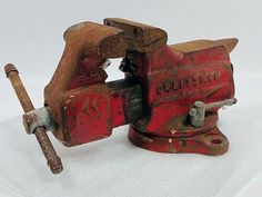 an old red bench vice with a wrench on it