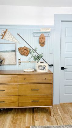 a wooden dresser sitting next to a white door in a room with blue walls and wood flooring