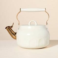 a white tea kettle with a gold handle