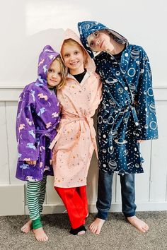 three children standing next to each other in bathrobes and wearing matching outfits with stars on them