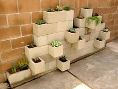 several cement planters with succulents on them against a brick wall in front of a building