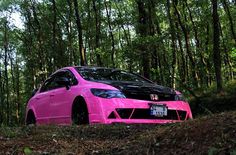 a pink car is parked in the woods