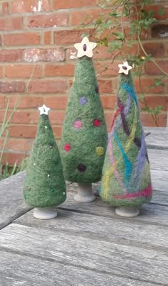 three small christmas trees sitting on top of a wooden table