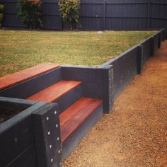 a wooden bench sitting next to a lush green field