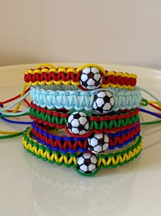 four bracelets with soccer balls on them sitting on a table next to each other