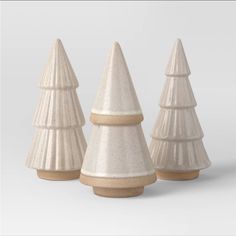 three white ceramic christmas trees with brown bases