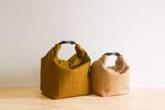 two bags sitting side by side on top of a wooden floor next to each other