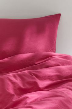 an unmade bed with bright pink sheets and pillowcases on top of it