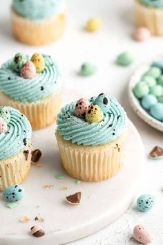 three cupcakes with blue frosting and chocolate eggs