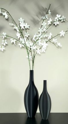 two black vases with white flowers in them