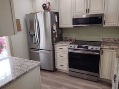 a kitchen with white cabinets and stainless steel appliances, including an oven, refrigerator, microwave, dishwasher and stove