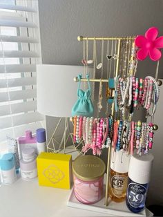 a white table topped with lots of bracelets and bottles next to a light fixture