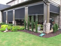 a patio covered in plants and flowers next to a brick building with an awning